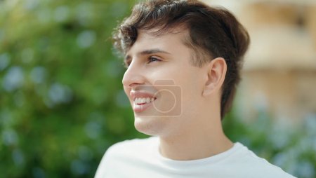Téléchargez les photos : Non binary man smiling confident looking to the side at park - en image libre de droit