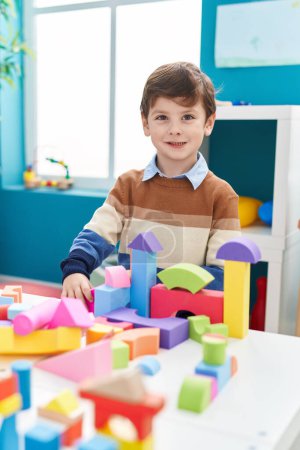Foto de Adorable hispanic boy playing with construction blocks standing at kindergarten - Imagen libre de derechos