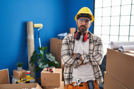 Photo for Young hispanic man with beard working at home renovation skeptic and nervous, disapproving expression on face with crossed arms. negative person. - Royalty Free Image