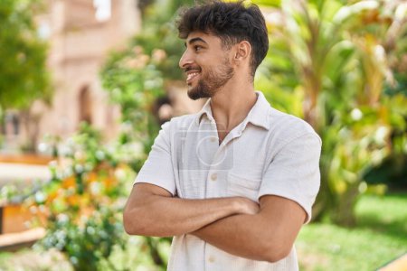 Téléchargez les photos : Jeune homme arabe souriant confiant debout avec les bras croisés geste au parc - en image libre de droit