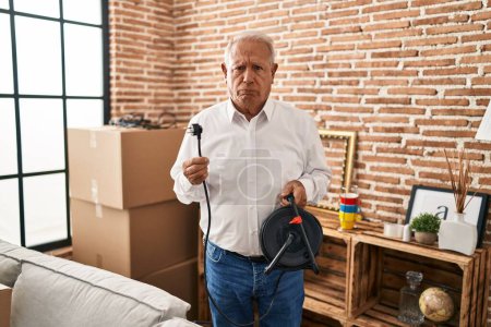 Photo for Senior man with grey hair holding extension plug skeptic and nervous, frowning upset because of problem. negative person. - Royalty Free Image