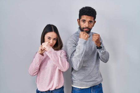 Téléchargez les photos : Young hispanic couple standing together ready to fight with fist defense gesture, angry and upset face, afraid of problem - en image libre de droit