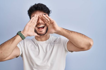Téléchargez les photos : Hispanic man with beard standing over white background smiling cheerful playing peek a boo with hands showing face. surprised and exited - en image libre de droit