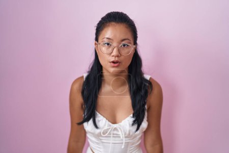 Téléchargez les photos : Asian young woman standing over pink background scared and amazed with open mouth for surprise, disbelief face - en image libre de droit