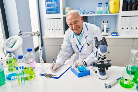Foto de Hombre mayor vistiendo uniforme científico midiendo líquido en laboratorio - Imagen libre de derechos