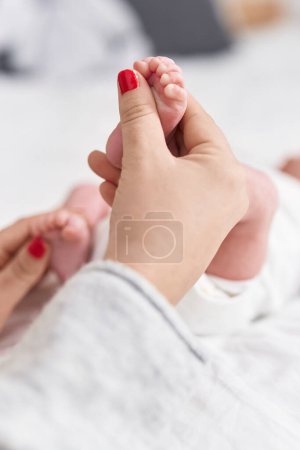 Téléchargez les photos : Adorable bébé caucasien couché sur le lit ayant massage des pieds dans la chambre - en image libre de droit