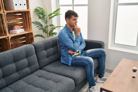 Téléchargez les photos : Jeune homme hispanique patient stressé assis sur le canapé à la clinique de psychologie - en image libre de droit