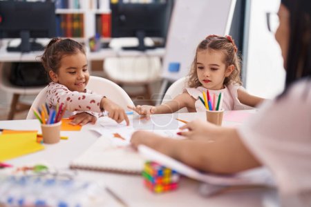 Foto de Two kids preschool students sitting on table drawing on paper at classroom - Imagen libre de derechos