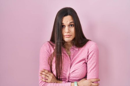 Téléchargez les photos : Young hispanic woman standing over pink background shaking and freezing for winter cold with sad and shock expression on face - en image libre de droit