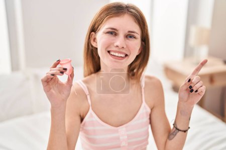 Téléchargez les photos : Beautiful woman holding menstrual cup smiling happy pointing with hand and finger to the side - en image libre de droit