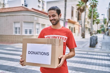 Téléchargez les photos : Bel homme hispanique tenant boîte de dons en plein air - en image libre de droit
