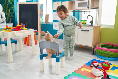 Téléchargez les photos : Adorable bambin hispanique jouant avec la cuisine de jeu et des jouets à la maternelle - en image libre de droit