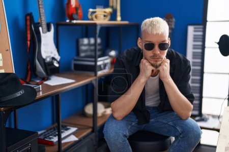 Téléchargez les photos : Young caucasian man artist sitting with serious expression at music studio - en image libre de droit