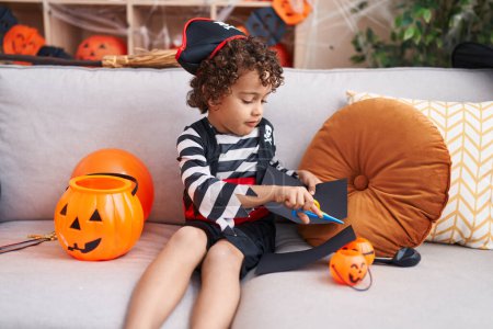 Photo for Adorable hispanic boy having halloween party drawing on balloon at home - Royalty Free Image