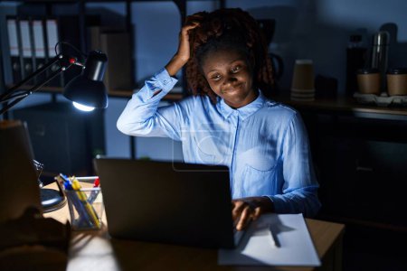 Foto de Mujer africana que trabaja en la oficina por la noche confunde y se pregunta acerca de la pregunta. incierto con la duda, pensando con la mano en la cabeza. concepto pensativo. - Imagen libre de derechos