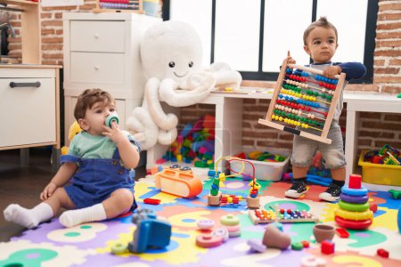 Téléchargez les photos : Two kids playing with toys sitting on floor at kindergarten - en image libre de droit