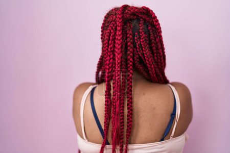 Foto de African american woman with braided hair standing over pink background standing backwards looking away with crossed arms - Imagen libre de derechos