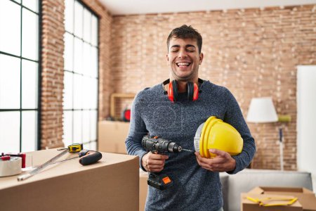 Foto de Joven hombre hispano trabajando en casa renovación sonriendo y riendo duro en voz alta porque divertido chiste loco. - Imagen libre de derechos