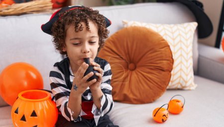 Photo for Adorable hispanic boy having halloween party inflating balloon at home - Royalty Free Image