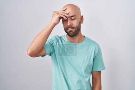 Foto de Middle age bald man standing over white background worried and stressed about a problem with hand on forehead, nervous and anxious for crisis - Imagen libre de derechos
