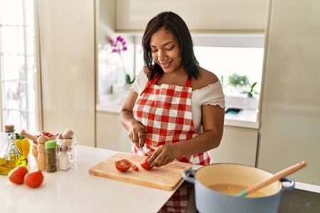 Téléchargez les photos : Hispanic brunette woman cooking cutting tomatoes at the kitchen - en image libre de droit