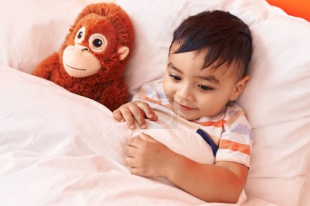 Photo for Adorable hispanic toddler smiling confident lying on bed with monkey doll at bedroom - Royalty Free Image