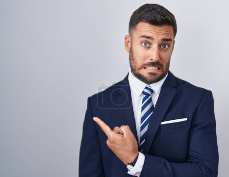 Téléchargez les photos : Handsome hispanic man wearing suit and tie pointing aside worried and nervous with forefinger, concerned and surprised expression - en image libre de droit