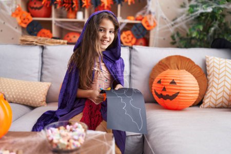 Téléchargez les photos : Adorable hispanique fille portant halloween costume coupe chauve-souris papier à la maison - en image libre de droit
