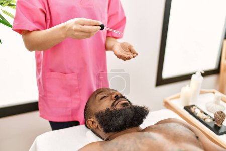 Téléchargez les photos : Jeune homme afro-américain ayant un traitement facial de la peau au centre de beauté - en image libre de droit