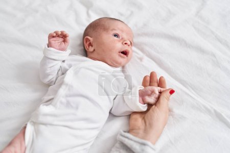 Téléchargez les photos : Adorable caucasian baby lying on bed at bedroom - en image libre de droit