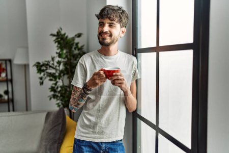 Foto de Joven hombre hispano sonriendo confiado bebiendo café en casa - Imagen libre de derechos