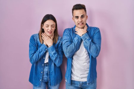 Photo for Young hispanic couple standing over pink background shouting suffocate because painful strangle. health problem. asphyxiate and suicide concept. - Royalty Free Image