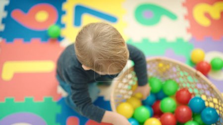 Photo for Adorable blond toddler playing with balls sitting on floor at kindergarten - Royalty Free Image