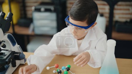 Photo for Adorable hispanic boy student holding molecules toy at laboratory classroom - Royalty Free Image