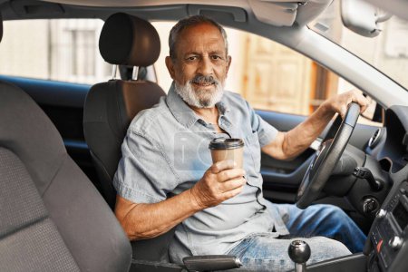 Téléchargez les photos : Homme âgé aux cheveux gris buvant du café assis en voiture dans la rue - en image libre de droit