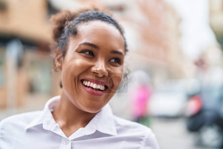 Téléchargez les photos : Afro-américaine femme souriant confiant regardant vers le côté à la rue - en image libre de droit