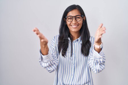 Téléchargez les photos : Jeune femme hispanique portant des lunettes souriant joyeuse offrant des mains donnant assistance et acceptation. - en image libre de droit