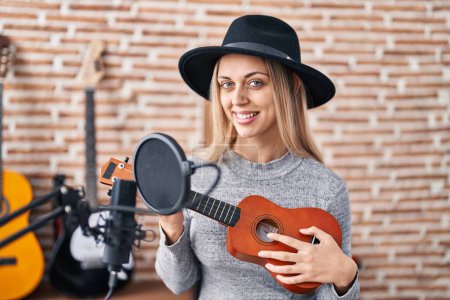 Téléchargez les photos : Jeune femme artiste chantant chanson jouant ukelele au studio de musique - en image libre de droit