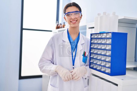 Photo for Young beautiful hispanic woman scientist smiling confident standing at laboratory - Royalty Free Image