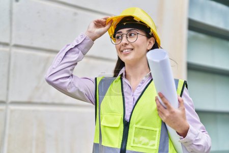 Photo for Young hispanic woman architect holding blueprints at street - Royalty Free Image