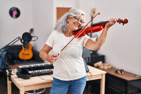 Photo for Middle age woman musician playing violin at music studio - Royalty Free Image