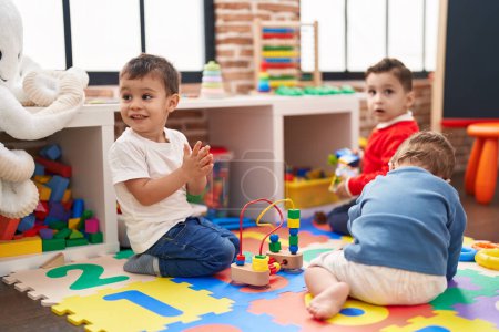 Foto de Grupo de niños jugando con juguetes sentados en el suelo en el jardín de infantes - Imagen libre de derechos