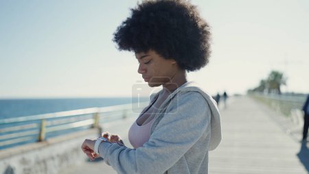 Téléchargez les photos : African american woman using stopwatch standing at seaside - en image libre de droit