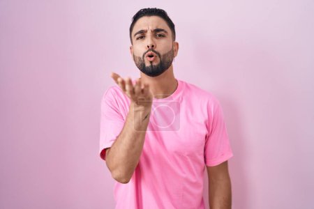 Téléchargez les photos : Hispanic young man standing over pink background looking at the camera blowing a kiss with hand on air being lovely and sexy. love expression. - en image libre de droit