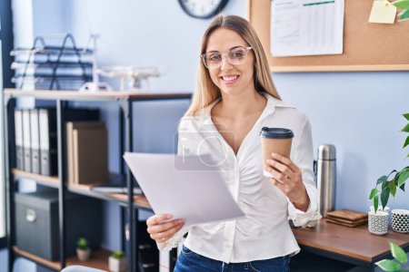 Photo for Young woman business worker reading document drinking coffee at office - Royalty Free Image
