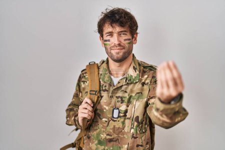 Foto de Hispanic young man wearing camouflage army uniform doing italian gesture with hand and fingers confident expression - Imagen libre de derechos