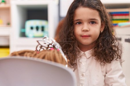 Téléchargez les photos : Adorable hispanic girl smiling confident playing with doll at kindergarten - en image libre de droit