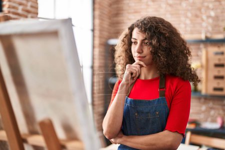 Photo for Young hispanic woman artist looking draw with doubt expression at art studio - Royalty Free Image