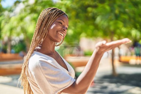 Téléchargez les photos : Afro-américaine femme souriant confiant faire me donner geste d'argent au parc - en image libre de droit