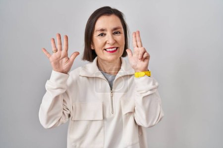 Foto de Middle age hispanic woman standing over isolated background showing and pointing up with fingers number eight while smiling confident and happy. - Imagen libre de derechos